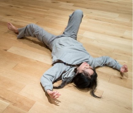 A person slowly on the floor with eyes closed